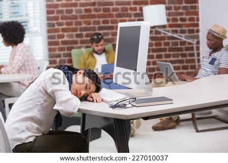 Casual young woman resting head on computer keyboard in the office