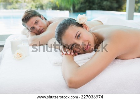 Portrait of relaxed young couple lying on massage table at spa center