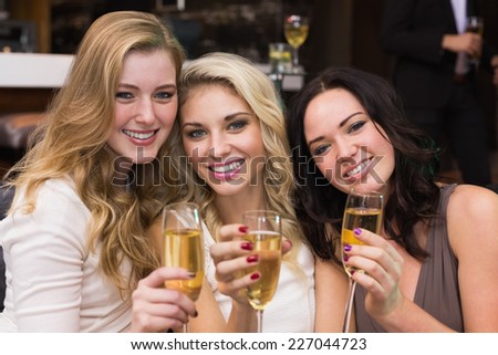 Happy friends drinking champagne together at the bar