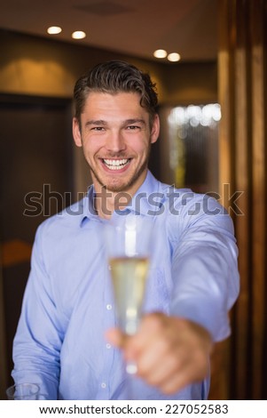 Handsome man holding flute of champagne at the bar