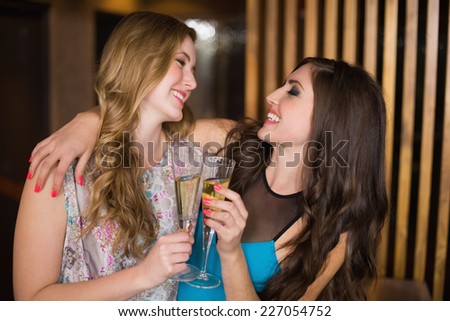 Attractive friends toasting with champagne at the bar