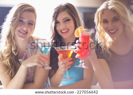 Attractive friends drinking cocktails together at the bar