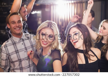 Stylish friends dancing and smiling at the bar