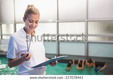 Pretty swimming coach standing poolside at the leisure center