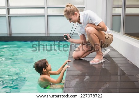 Pretty swimming coach showing boy his time at the leisure center