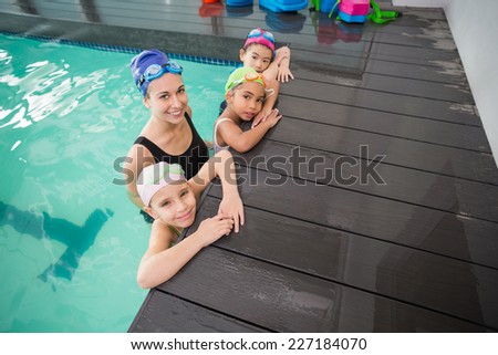 Cute swimming class and coach smiling at the leisure center