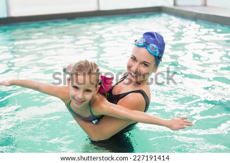 Cute little girl learning to swim with coach at the leisure center