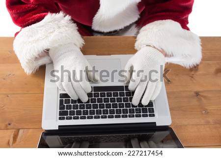 Santa is writing something on his laptop at the desk