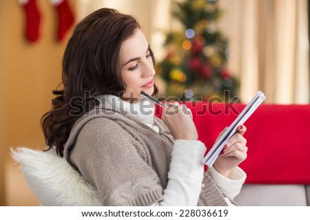 Brunette lying on the couch thinking about her christmas list at home in the living room