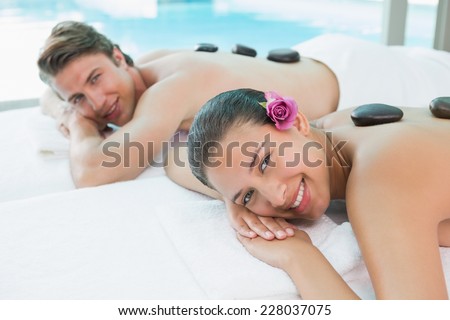 Side view portrait of a young couple enjoying stone massage at health farm
