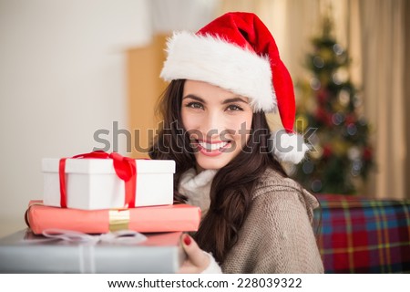 Festive brunette holding pile of gifts at christmas at home in the living room