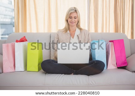 Pretty blonde shopping online with laptop at home in the living room