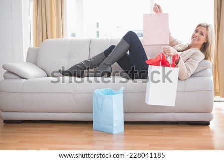 Woman lying on couch with shopping bags at home in the living room