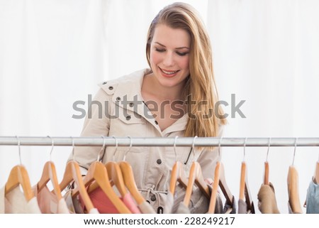 Pretty blonde looking through clothes rail in the store