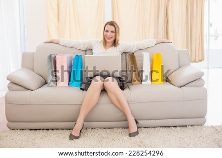 Pretty blonde shopping online with laptop at home in the living room