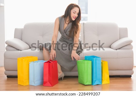 Elegant brunette looking in shopping bag on the couch at home in the living room