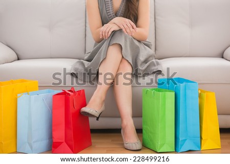 Elegant woman sitting on the couch with shopping bags at home in the living room