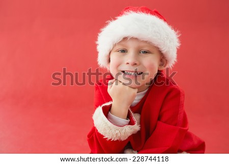 Cute little boy in santa costume on red background