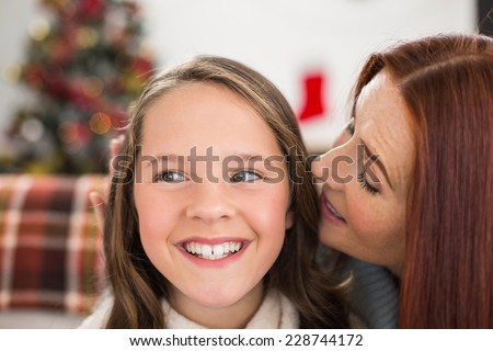 Mother telling her daughter a christmas secret at home in the living room