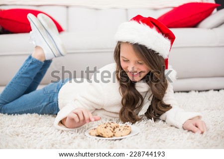 Festive little girl eating cookies at home in the living room