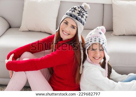 Mother and daughter smiling at camera at home in the living room