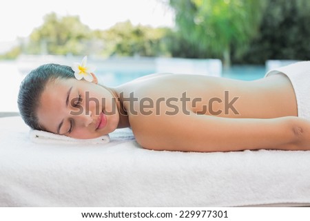 Side view of a beautiful young woman lying on massage table at spa center