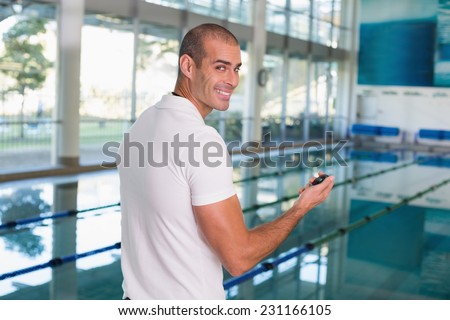Portrait of a swimming coach with stopwatch by the pool at the leisure center