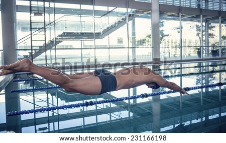 Side view of a fit swimmer diving into the pool at leisure center