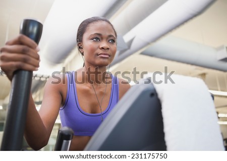 Fit woman working out on the cross trainer at the gym