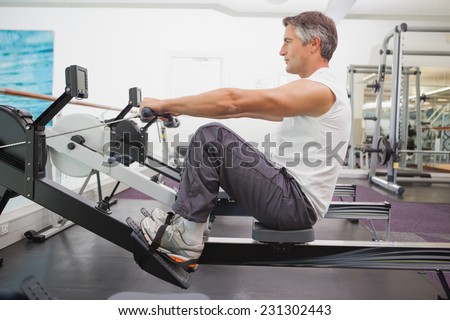 Fit man working out on rowing machine at the gym