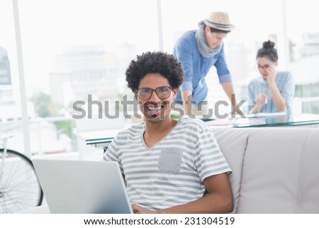 Young creative man using laptop on couch in creative office