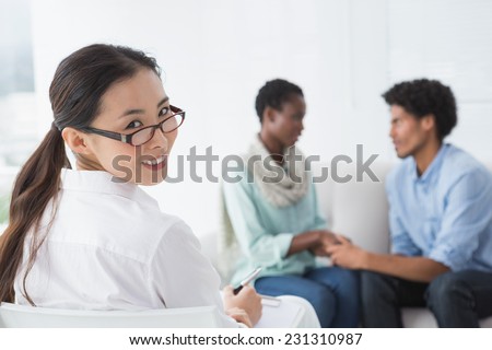 Reconciled couple smiling at each other in therapists office