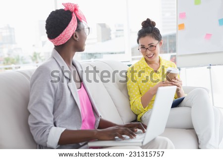 Young creative women chatting on the couch in creative office