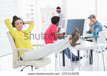 Young creative woman sitting with feet up in creative office