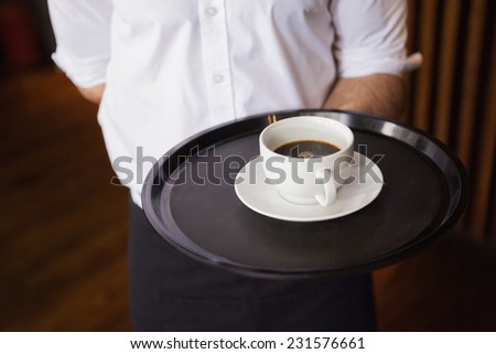 Waiter holding tray with coffee cup in a bar