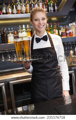 Pretty waitress holding a tray of champagne in a bar