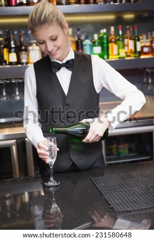 Cute woman in suit pouring champagne into flute in a bar