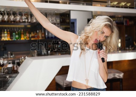 Blonde woman singing and dancing with hand up at the nightclub
