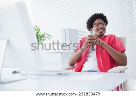 Relaxed businessman holding glass of milkshake in his office
