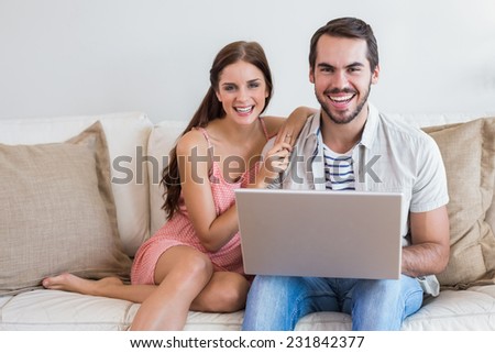 Hipster couple using laptop on couch at home in the living room