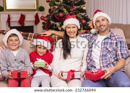 Festive family posing with gifts on the couch at home in the living room