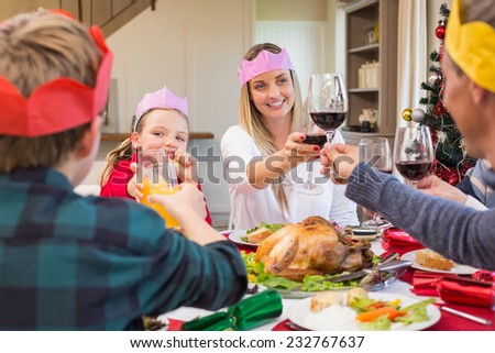 Family in party hat toasting at christmas dinner at home in the living room