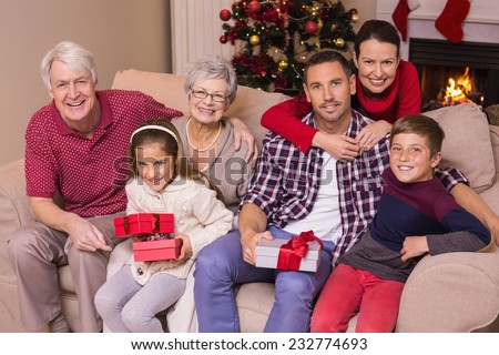 Multi generation family holding gifts on sofa at home in the living room