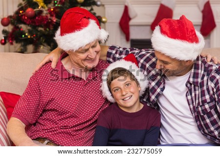 Portrait of grandfather father and son in santa hats at home in the living room
