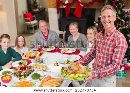 Man holding turkey roast with family at dining table at home in the living room