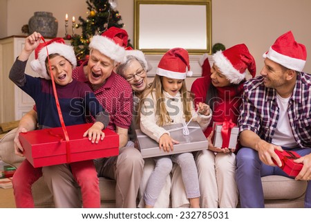 Festive multi generation family opening gifts together at home in the living room