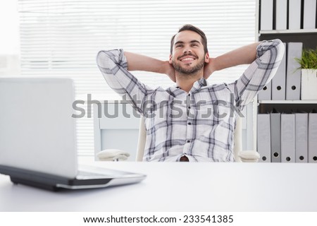 Casual businessman relaxing at desk leaning back in his office
