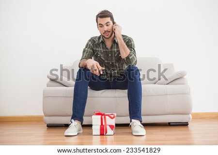 Confused man looking at gifts on floor at home in the living room
