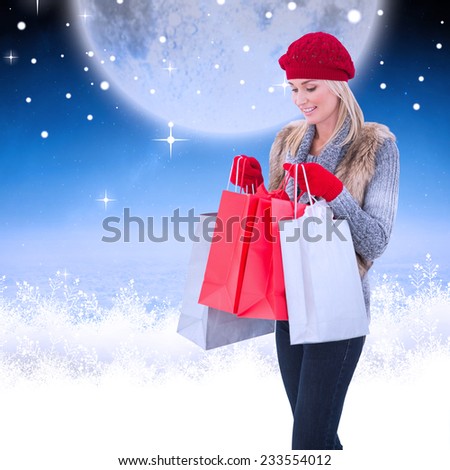 Blonde in winter clothes with shopping bags against white clouds under blue sky