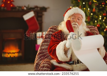 Concentrated santa writing his list on a scroll at home in the living room